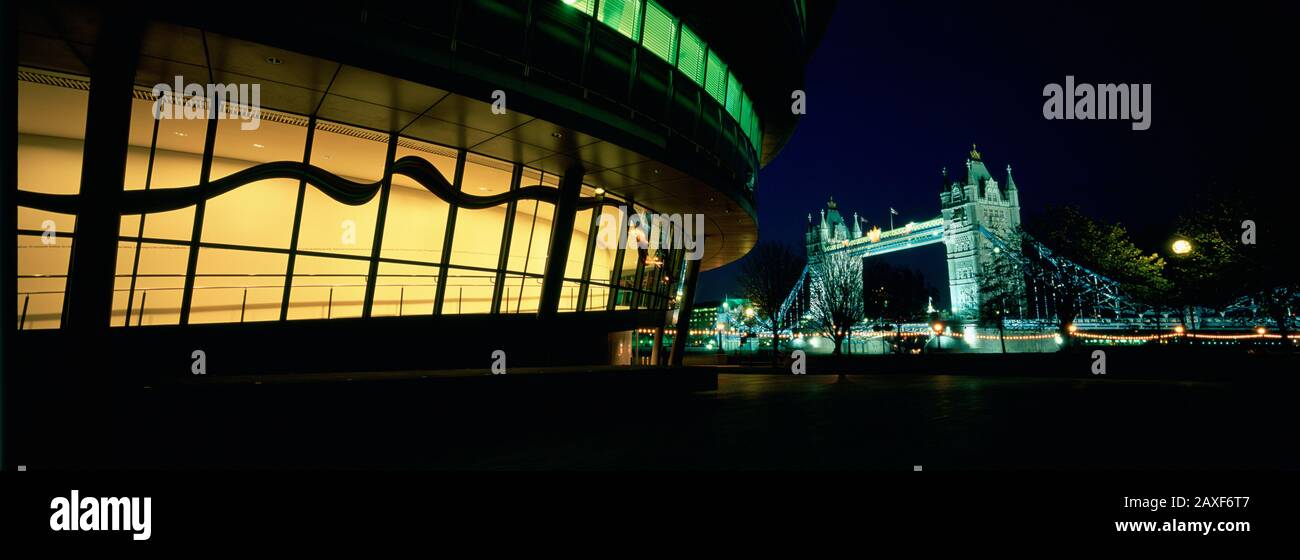 Das Regierungsgebäude wurde nachts mit einer Brücke im Hintergrund beleuchtet, Rathaus, Tower Bridge, London, England Stockfoto
