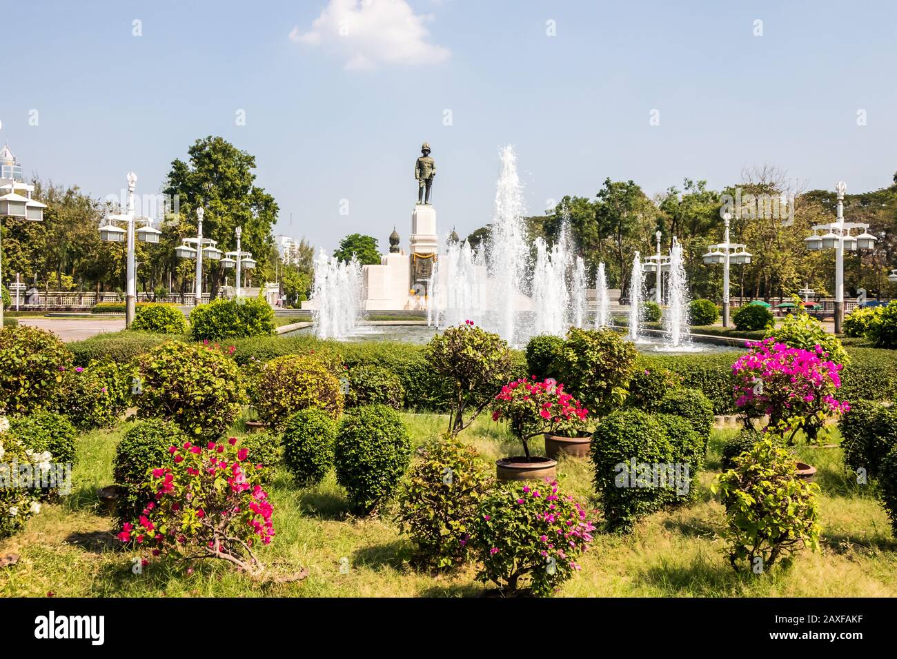 Blick auf Blumen und Springbrunnen mit Statue von König Rama IV. Im Hintergrund, Lumphini Park, Bangkok, Thailand Stockfoto