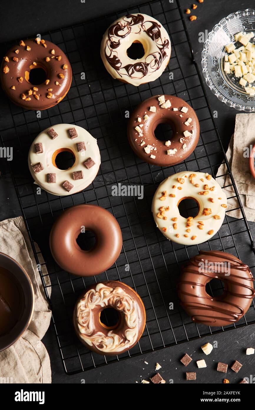 Vertikale Schuss von köstlichen Donuts in der Schokolade Glasur bedeckt Auf einem schwarzen Küchentisch Stockfoto