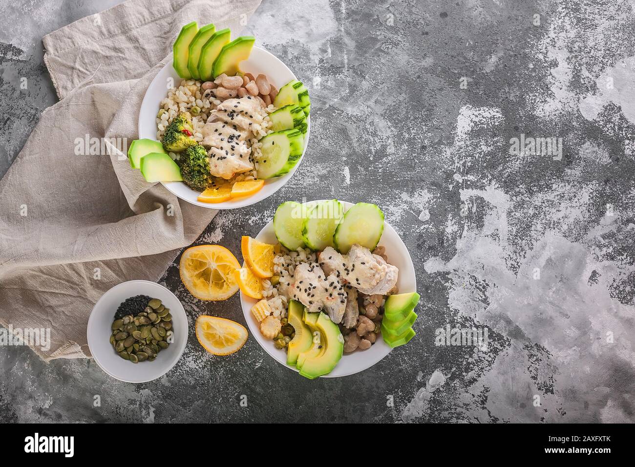 Buddha-Schüssel mit Hühnerfleisch, Bulgur, weißen Bohnen, Quinoa, Avocado, Zitrone und frischer Gurke. Kopierbereich Stockfoto