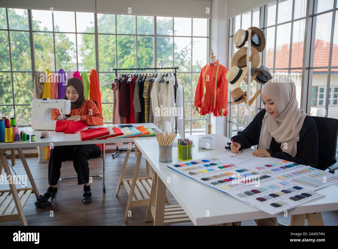 Kleine Unternehmen von Moslem-Frauen Modedesignerin, Die Mit Smartphone und Tablet Mit Kleider im Bekleidungsgeschäft arbeitet und verwendet Stockfoto