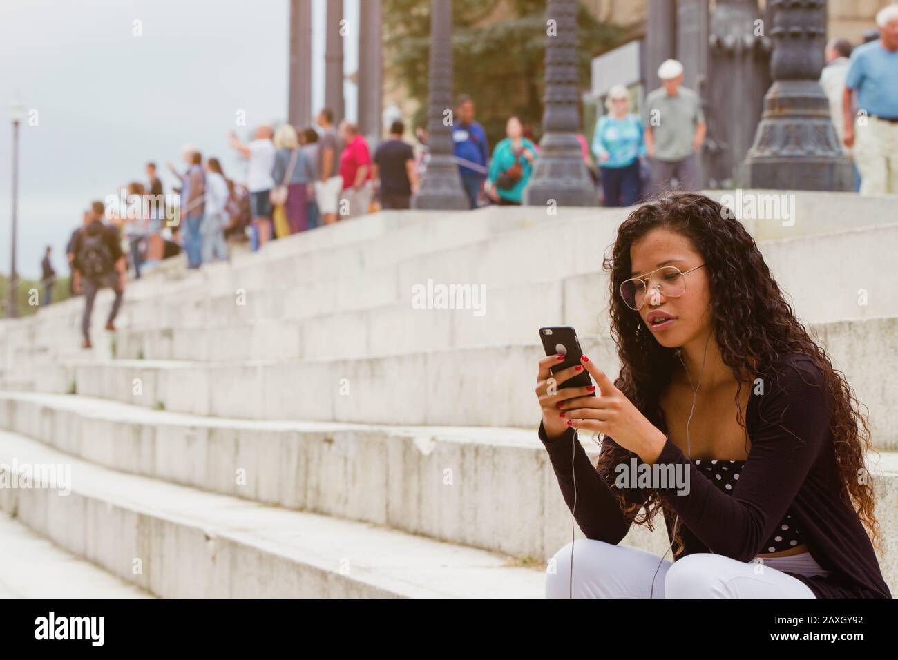 Attraktive Frau textet auf dem Smartphone auf der Treppe. Leerer Platz für Text Stockfoto