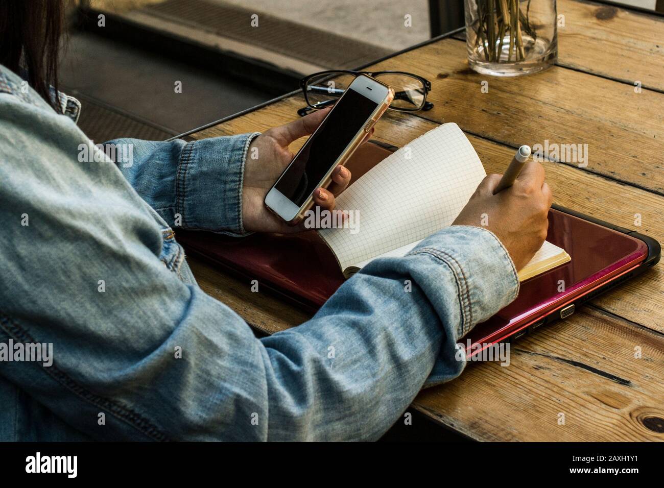 Frau Enterpreneur sucht auf dem Smartphone und schreibt die Informationen auf Stockfoto