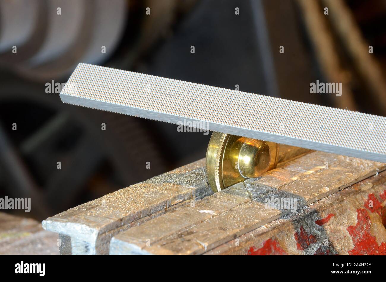 Prüfdatei, die für ein Messingelement in einem roten Schraubstock verwendet wird Stockfoto