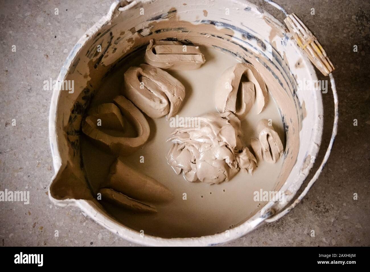Tonstücke weichen in Wasser in einem Eimer in der oberen Ansicht aus. Kreativer Studio Töpfer. Workplace Wizard Crock Keramik Stockfoto