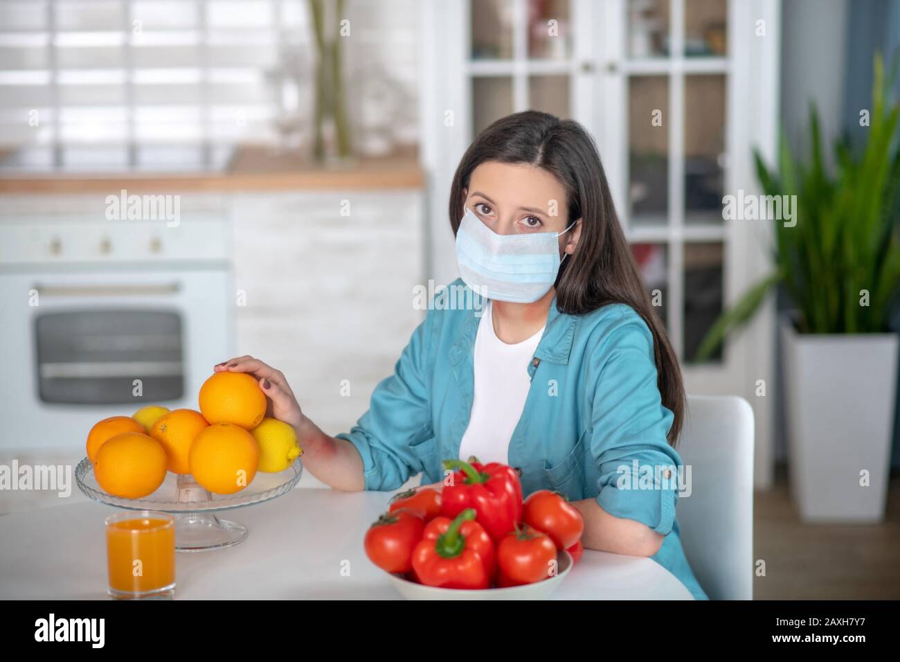 Frau, die in ihrer Küche eine medizinische Maske trägt Stockfoto