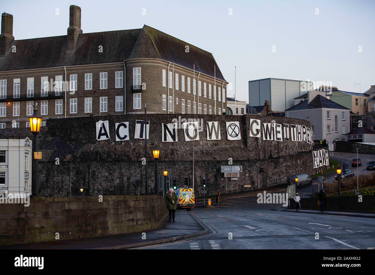 Carmarthen, Großbritannien. Februar 2020. Mitglieder des Extinction Rebellion in Carmarthen entfachen Banner, die "Act Now" ("Gweithredwch Nawr" auf walisisch) auf den Seiten der County Hall in Carmarthen lesen. Kredit: Gruffydd Ll. Thomas/Alamy Live News Stockfoto