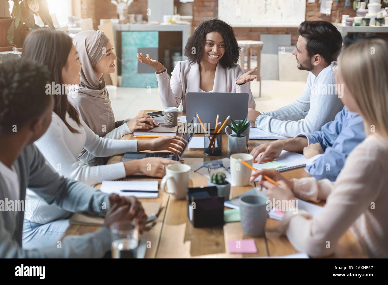 Fröhliche junge Geschäftsgruppe mit morgendlicher Unterweisung im Büro Stockfoto