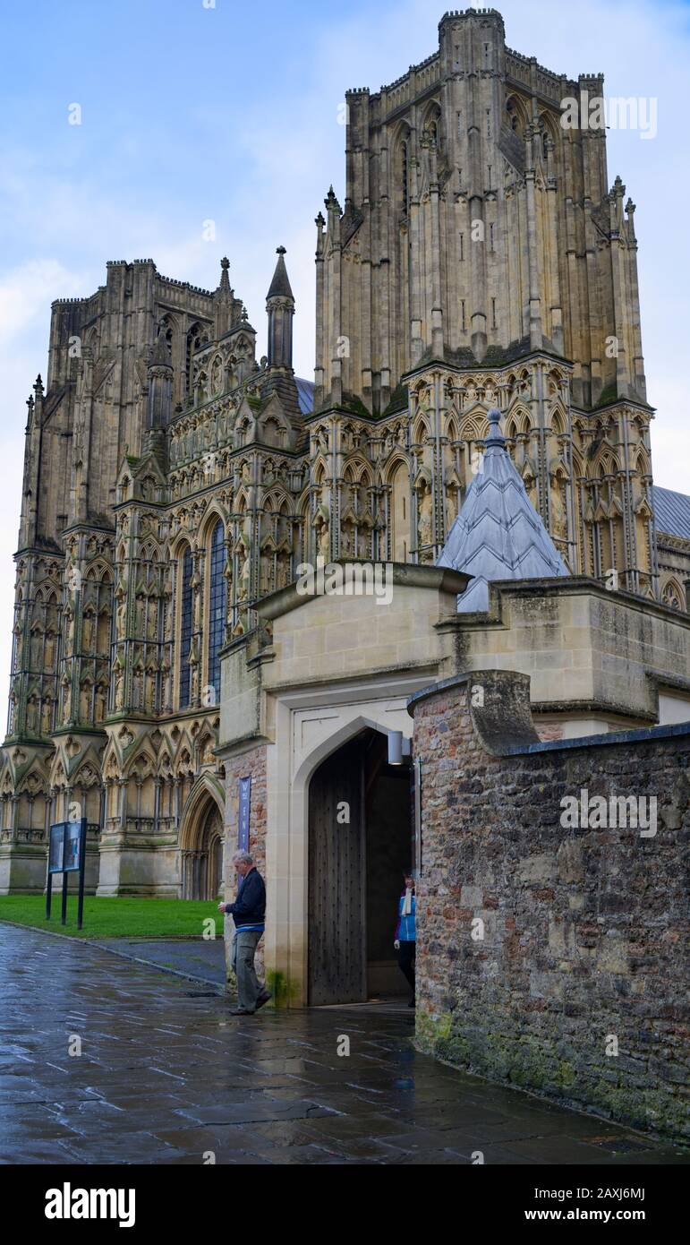 Eine Dame und ein Mann verlassen den Haupteingang der Wells Cathedral Stockfoto
