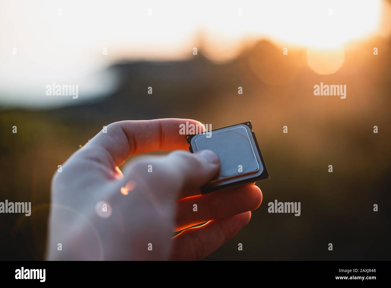 Person, die einen Computerprozessor bei Sonnenuntergang in der Hand hält. Sichtbild. CPU-Konzept. Stockfoto
