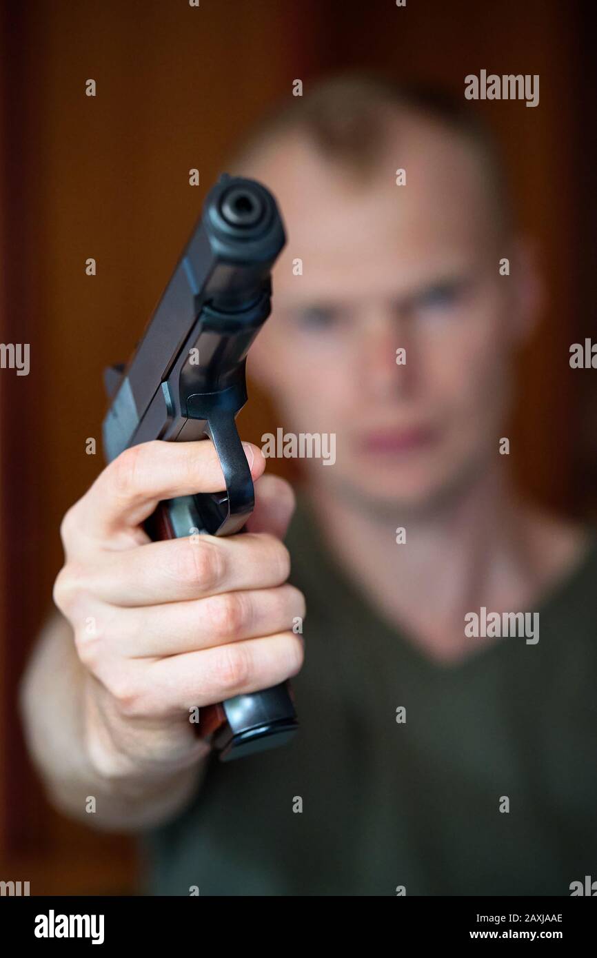 Ein Mann zielt auf seine halbautomatische Pistole. Selektiv auf die Vorderseite der Waffe fokussiert Stockfoto