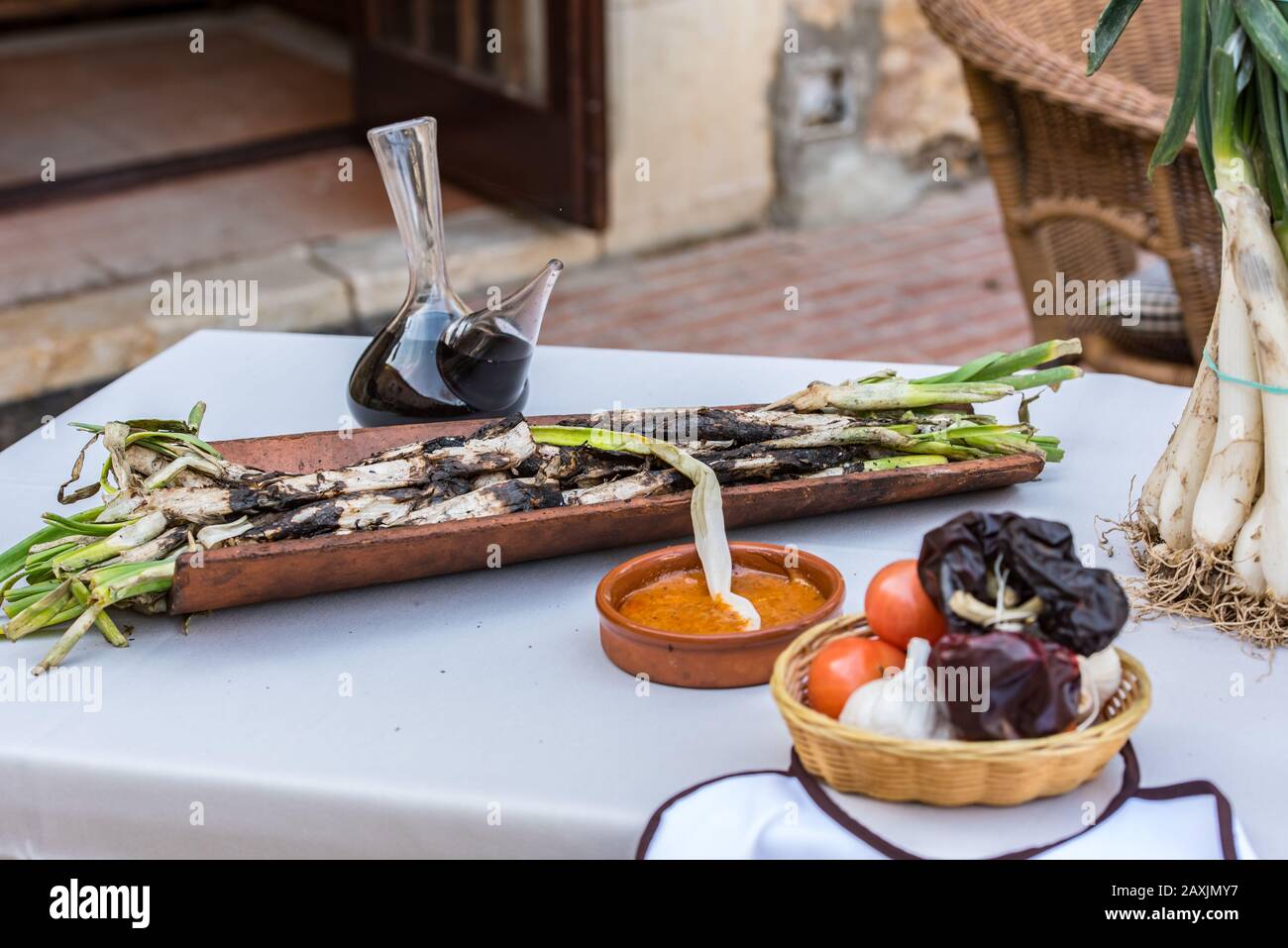 Gebratene Calcots Zwiebeln auf dem Teller mit Romesco Sauce - traditionelles katalanisches Wintergericht. Stockfoto