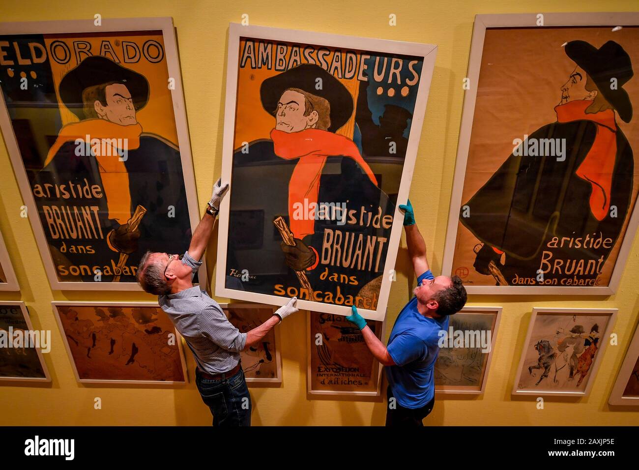 Galerie-Mitarbeiter hängen ein Aristide Bruant Poster aus dem Jahr 1892, als sie die Ausstellung "Touloure-Lautrec" und "Masters of Montmartre" in der Victoria Art Gallery, Bath, in der erstmals eine komplette Sammlung von Touloure-Lautrec-Plakaten, viele davon selten, zusammen ausgestellt werden. Stockfoto