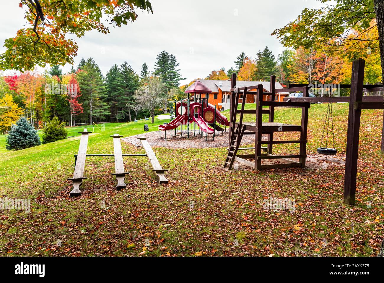 Spielplatz in einem Park, umgeben von farbenfrohen Herbstbäumen an einem wolkigen Morgen. Herbstlaub. Stockfoto
