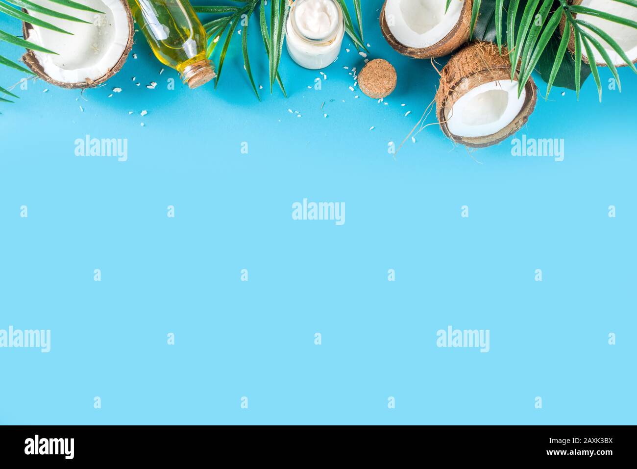 Kokosöl im Glasbecher mit tropischen Blättern und frischer Kokosnuss. Konzept für organische mct-Öle. Türkis, Aquamarin Hintergrund Stockfoto