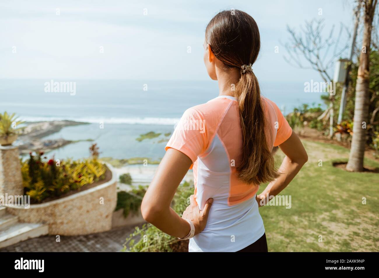 Fitness-Sport-Mädchen nach intensivem Lauf, junge attraktive Läuferin, die nach dem Joggen im Freien am Strand von der Klippe aus die Pause macht Stockfoto