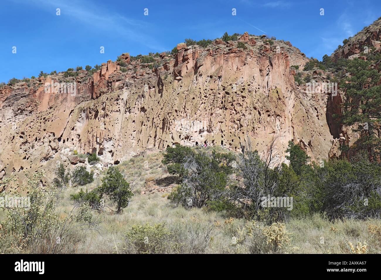 Unidentifizierbare Menschen auf Wanderwegen entlang von Klippen und Ruinen der angestammten Pueblo-Völker im Frijoles Canyon im Bandelier National Monument nahe Los Alam Stockfoto