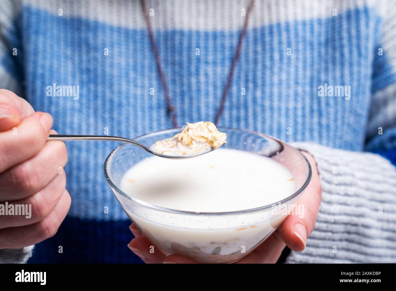 Frau isst zum Frühstück eine Schüssel mit Müsli und Cornflakes, gerolltem Hafer. Ernährung und gesundes Lebenskonzept Stockfoto