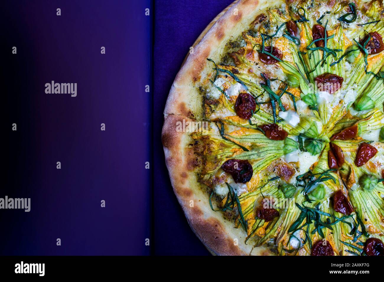 Hochwinkelige Nahaufnahme vegetarischer Pizza mit Ziegenkäse und Zucchini-Blumen. Stockfoto