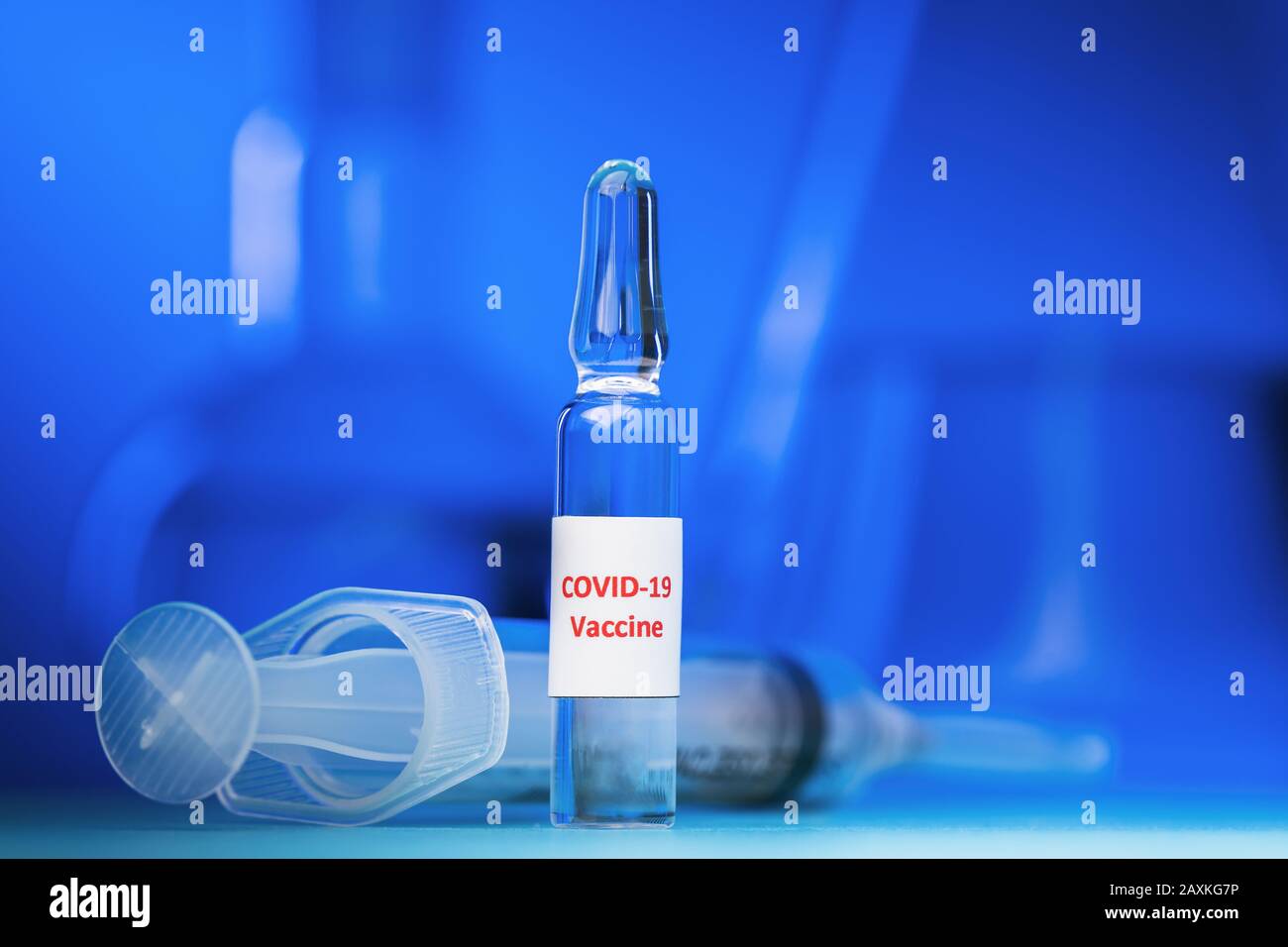 COVID-19-Impfstoffampulle mit Coronavirus auf blauem Hintergrund, Nahaufnahme Stockfoto