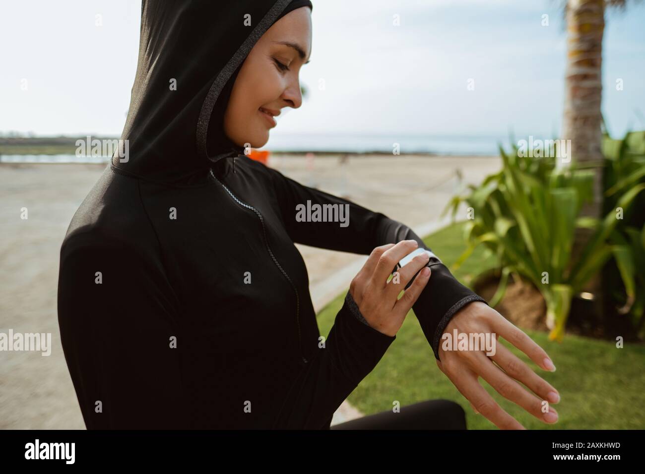 Junge muslimische Frau mit Schal, die eine elegante Uhr vor dem Joggen  aufsetzt Stockfotografie - Alamy