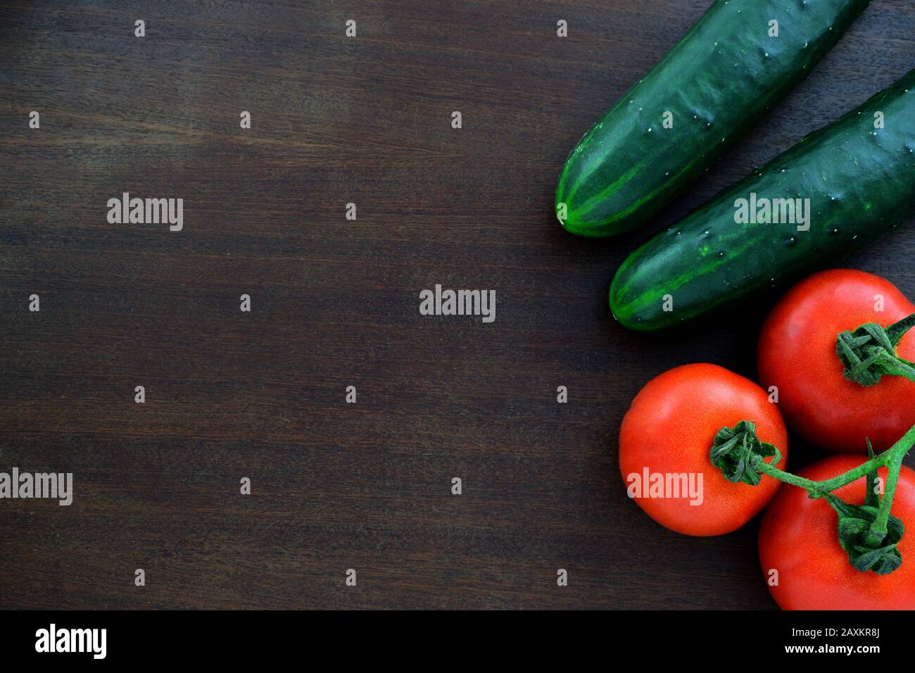 Zwei Gurken mit einem Bündel Tomaten auf einem alten Holztisch Stockfoto