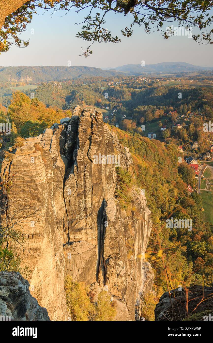 Kletterfelsen im Nationalpark Sächsische Schweiz. Elbsandsteingebirge mit Felsformation, Wälder in saisonalen Farben und Häuser im Autu Stockfoto