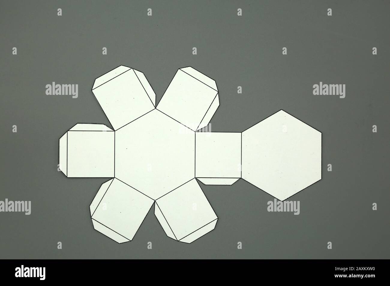 Geometrische Form aus Papier geschnitten und auf grauem Hintergrund fotografiert.Geometrienetz aus Sechseckigem Prisma. 2-dimensionale Form, die zu einem gefaltet werden kann Stockfoto