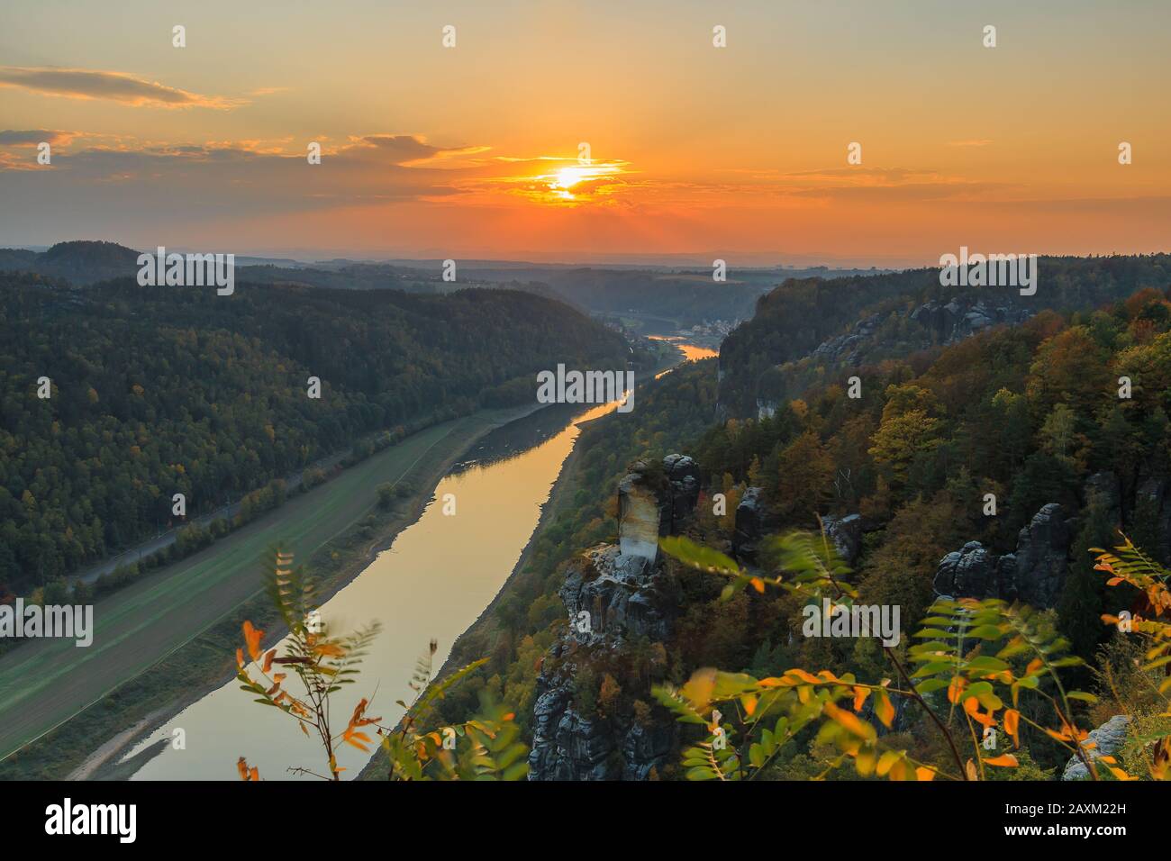 Blick von der Bastei-Brücke über das Elbtal im Nationalpark Sächsische Schweiz. Elbe bei Sonnenuntergang. Farbenfroher Himmel mit orangefarbener Sonne im Herbst Stockfoto