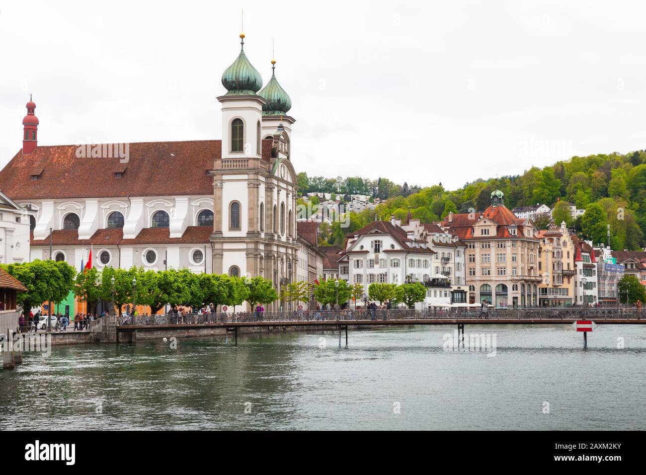 Luzerner, Schweiz - 7. Mai 2017: Straßenansicht Luzerner mit jesuitischer Kirche im Hintergrund, Touristen wandern an der Flussküste Stockfoto