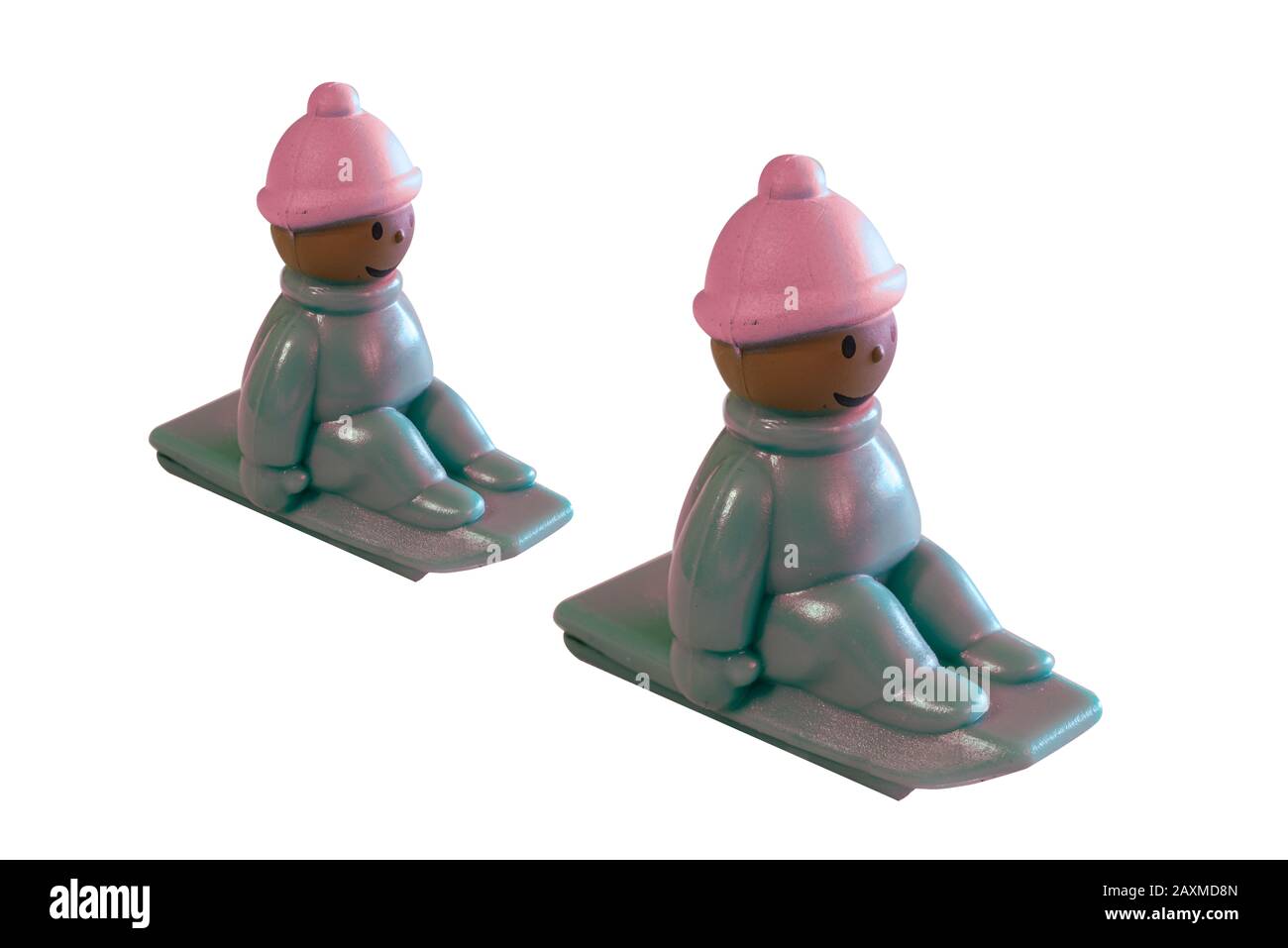 Kleines buntes Spielzeug für kleine Kinder eines Kindes, das auf einem Schlitten sitzt, der den Hügel hinuntergeht, mit einem Hut gegen die Kälte und den Fäusten, die eng am sitzen Stockfoto