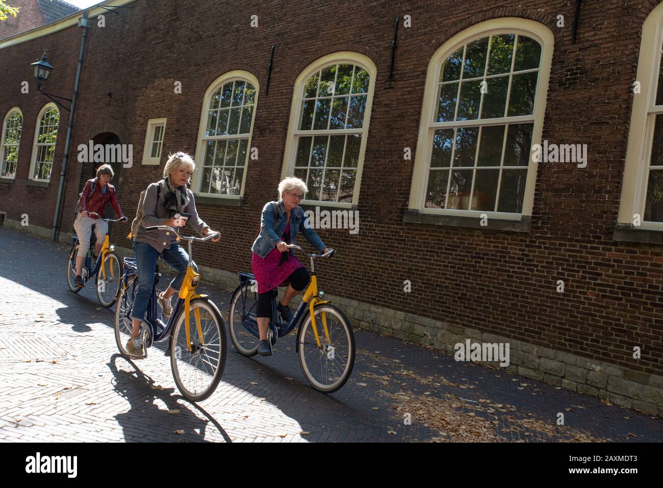 3 weiße toucern mittleren Alters, die durch die Straße von Delft, die Niederlande radeln. // 3 weibliche Touristen mittleren Alters, die durch die radeln Stockfoto