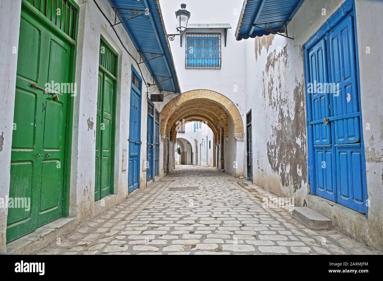 Typische gepflasterte und schmale Straße (Pacha-Straße) mit bunten Türen, Säulen und Arkaden in der historischen Medina von Tunis, Tunesien Stockfoto