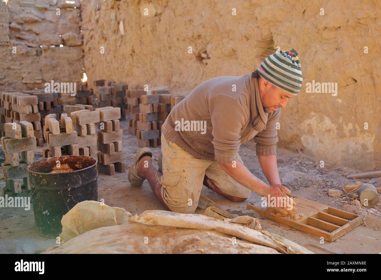 Tozeur, TUNESIA - 20. DEZEMBER 2019: Ein ortskundiger Arbeiter, der in einer Ziegelei in traditioneller Weise Backsteine macht. Mit einem Holzrahmen werden die Backsteine geformert. Stockfoto