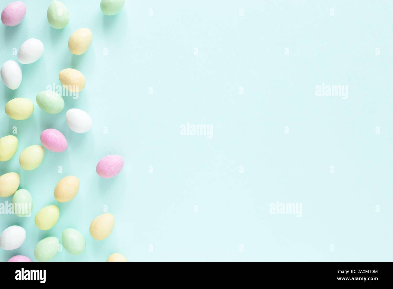 Farbige Osterbonbons auf türkisfarbenem Hintergrund. Oster-Minimal-Karte. Stockfoto