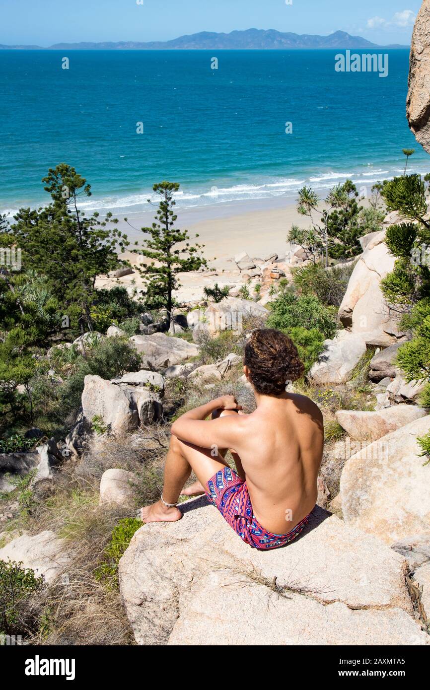 Junger Mann mit Haarbün und Badeanzug, Blick auf den Ozean Stockfoto