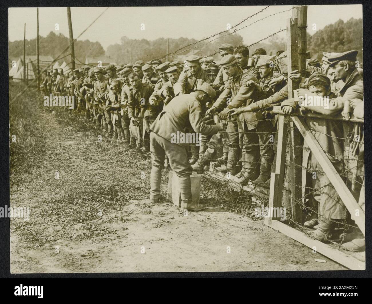 National Archive Collection War. (158-0753) deutsche Gefangene, die darauf bedacht waren, etwas Wasser zu bekommen, die Front in Frankreich. Deutsche Kriegsgefangene hinter Stachelbeter schauen sehnsüchtig auf welches Wasser Stockfoto