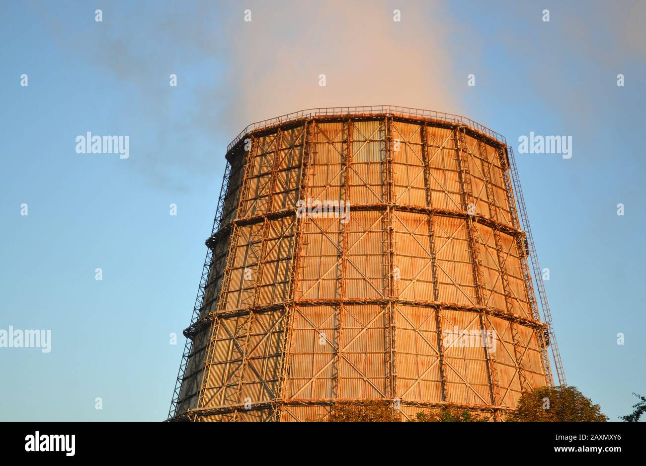 Großer Kamin des Wärmekraftwerks bei Sonnenuntergang bei Sonnenaufgang mit hellblauem Himmel mit dem Rauch aus dem Kamin Stockfoto