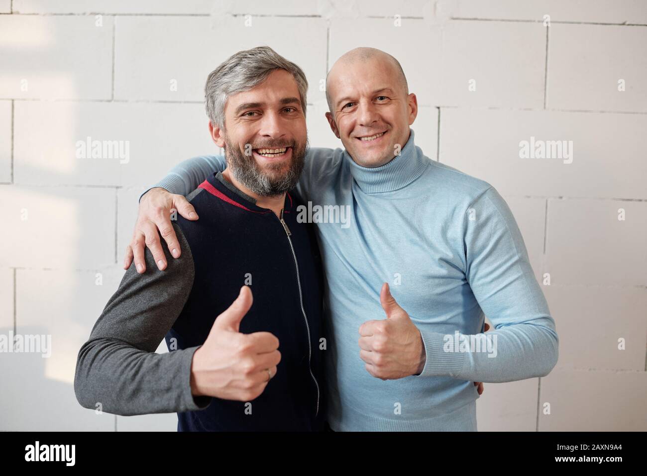 Portrait von positiv aufgeregten Freunden mittleren Alters, die Daumen hoch als Symbol der besten Freundschaft zeigen Stockfoto