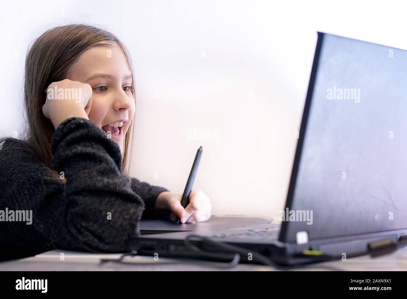 Mädchen zu Hause lernt, mit einem Tablet und einem Stift auf den Laptop zu zeichnen Stockfoto