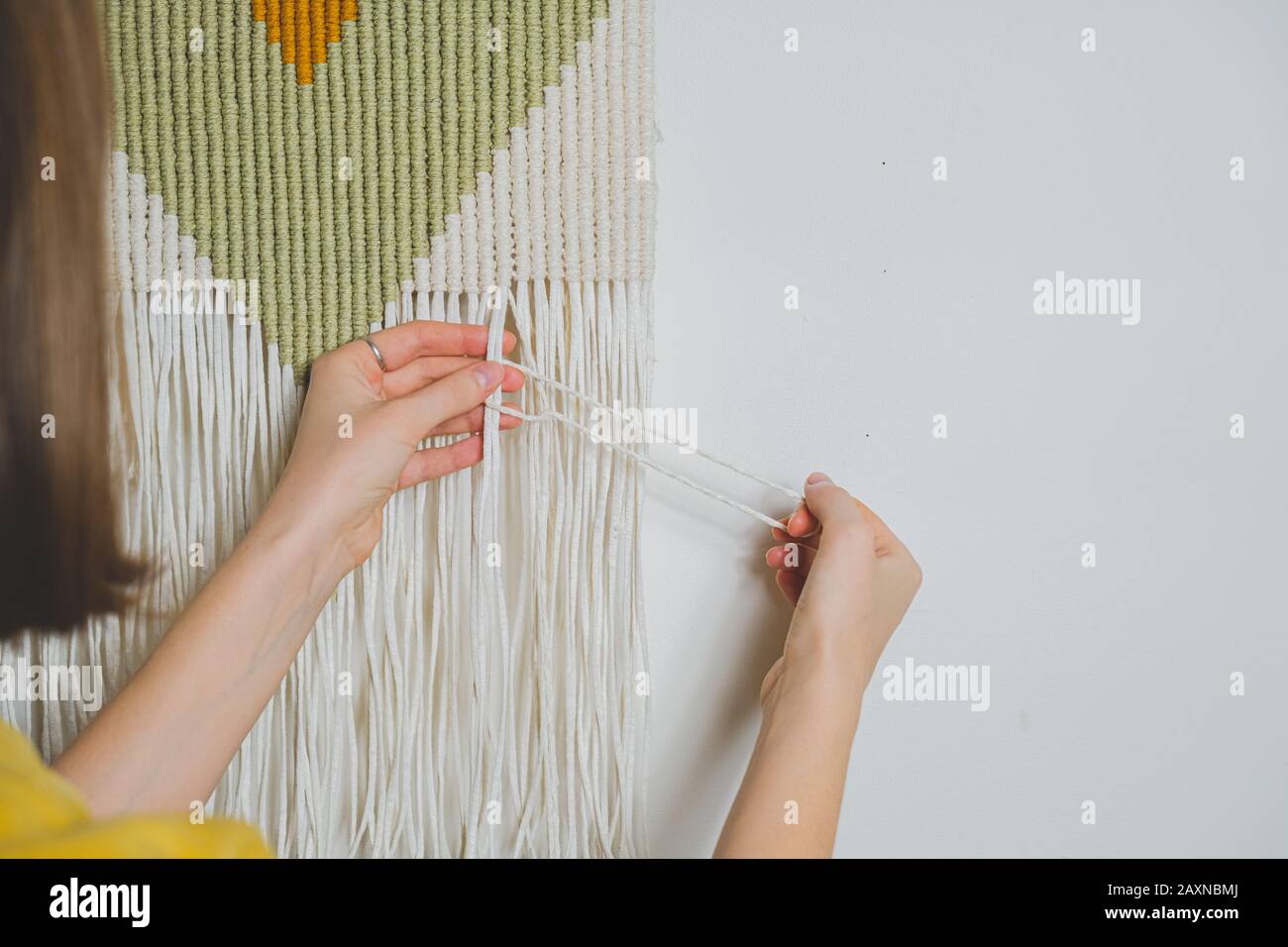 Frau, die macrame Handwerk macht. Handgefertigt aus einem Wanddekor mit Baumwollseil, Konzept des Hobbys oder der Handarbeit Stockfoto