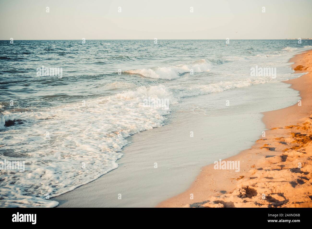Blick auf den Strandsand mit Meereswellen und weißem Schaumfilter Stockfoto
