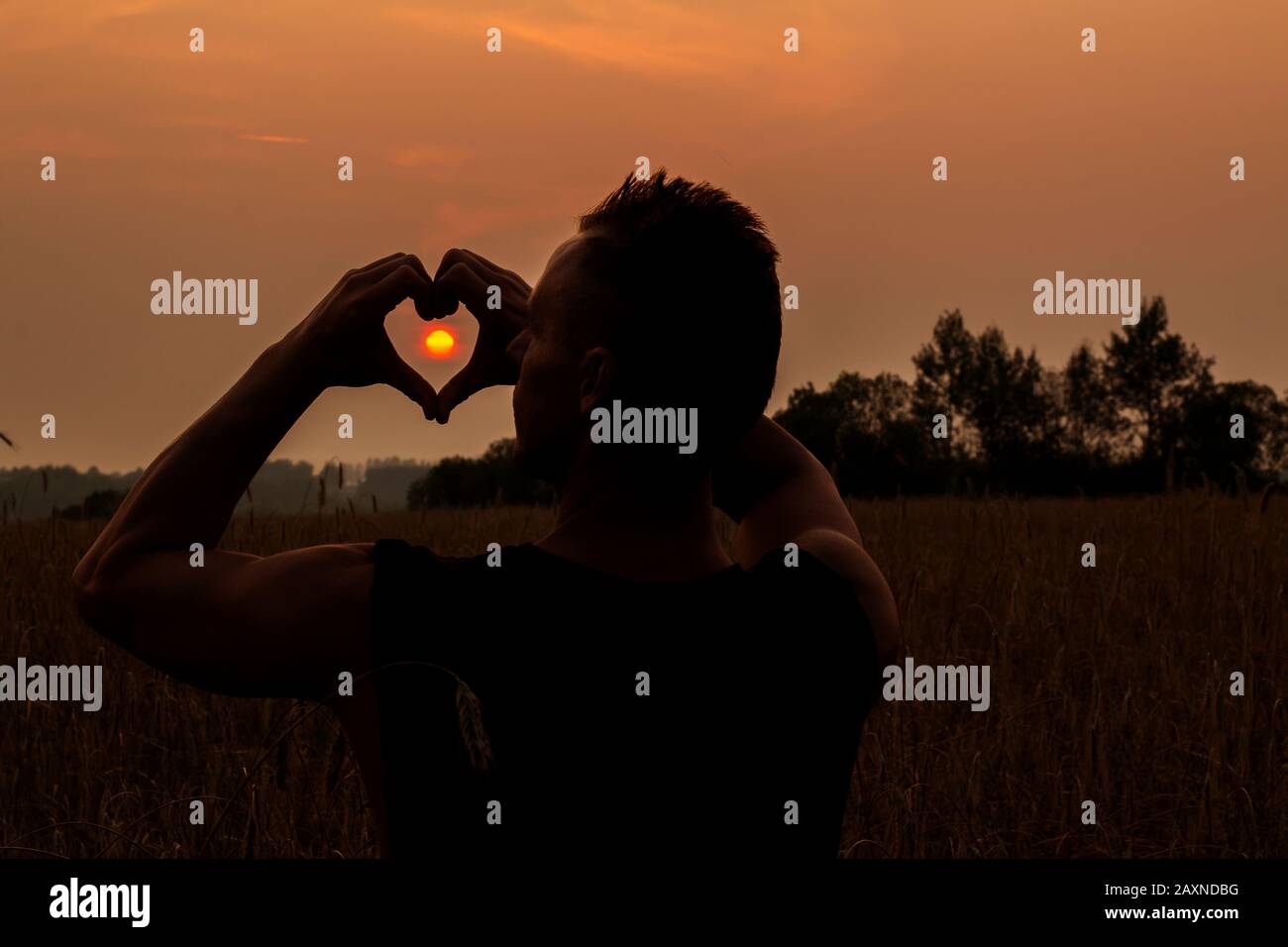 Ein Mann fängt die Sonne im Herzen von seinen Fingern. Stockfoto