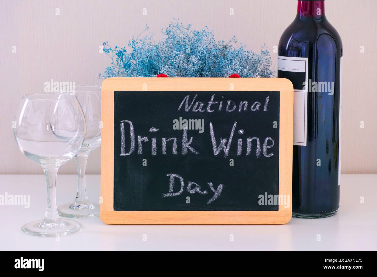 Tafel mit den Worten National Drink Wine Day auf dem Tisch mit einer Weinflasche und zwei Gläsern. Stockfoto