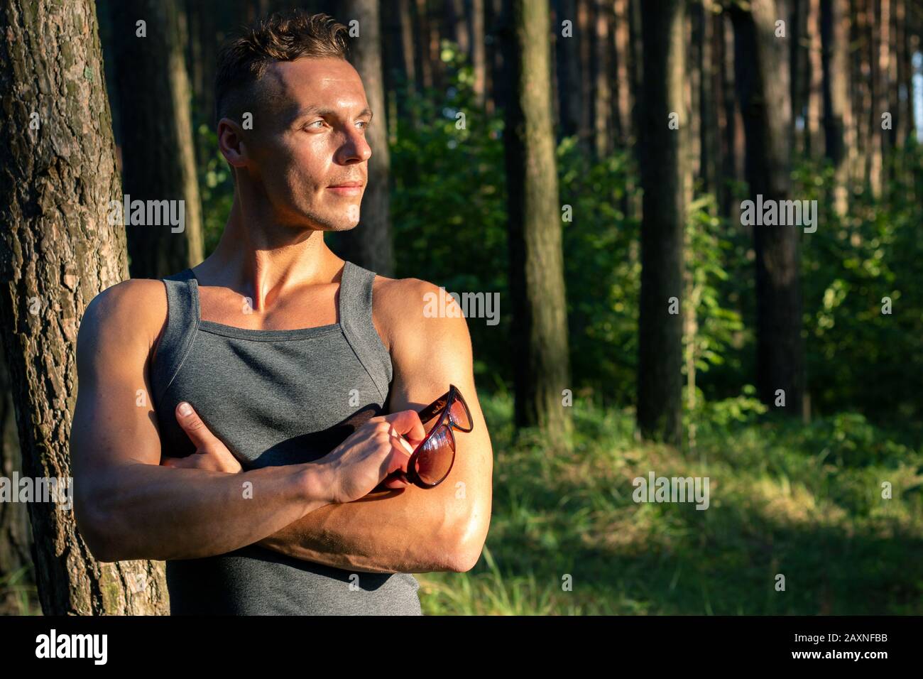 Ein sportlicher Mann im Wald, entspannend bei Sonnenuntergang. Stockfoto