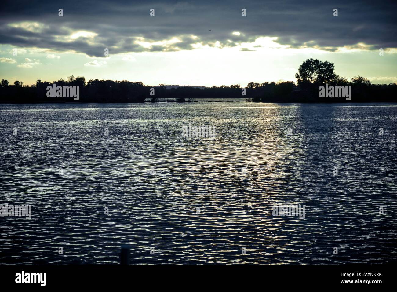 Dunkle Wolken bei Sonnenuntergang, Sonnenaufgang über der Wasseroberfläche, Filter Stockfoto