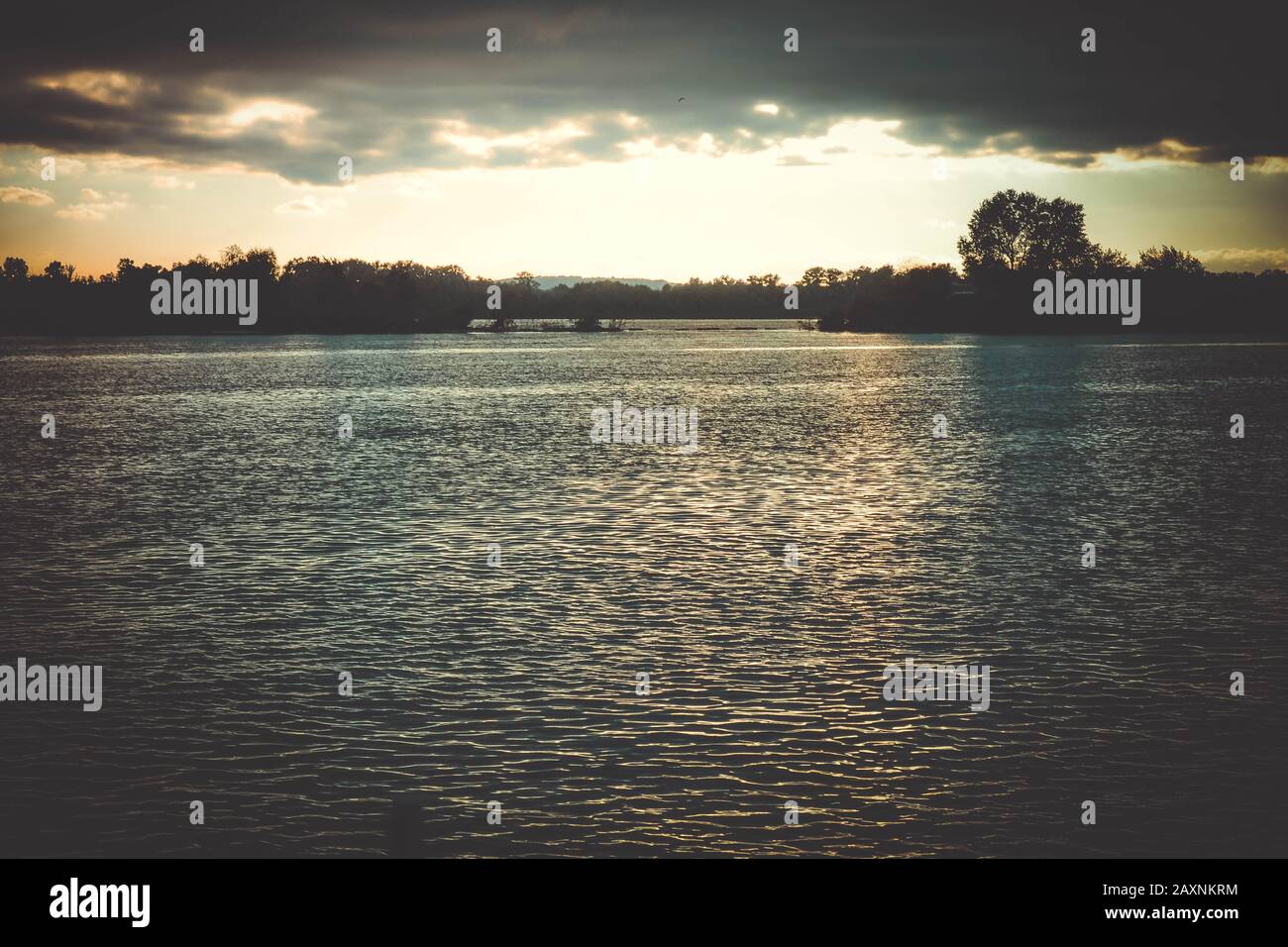 Dunkle Wolken bei Sonnenuntergang, Sonnenaufgang über der Wasseroberfläche, Filter Stockfoto