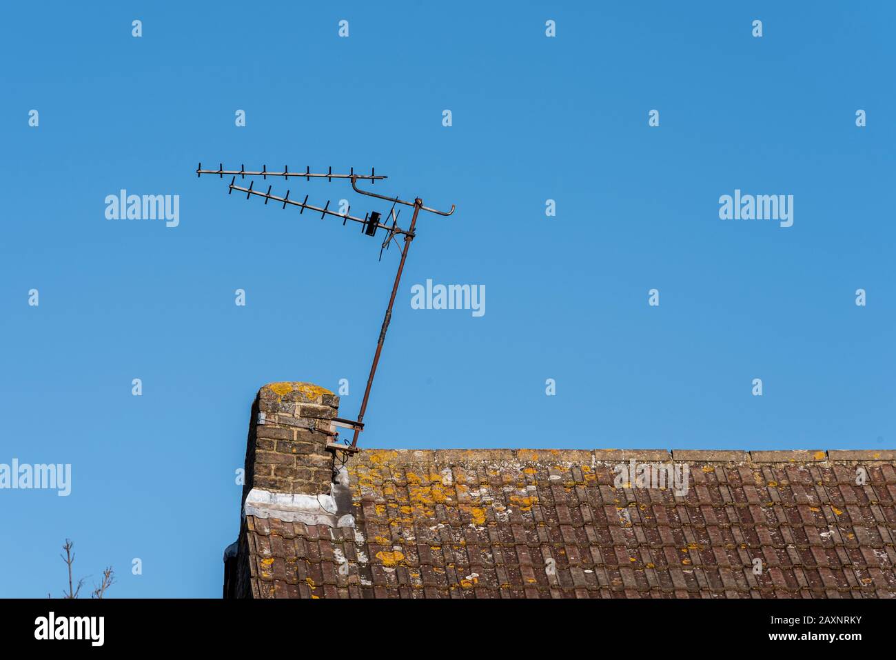 Eine Haus-TV-Antenne, beschädigt durch Storm Ciara, hängt schräg an einem Stummelschornstein. Extern montierte tv-Antenne auf dem Dach des Hauses Stockfoto