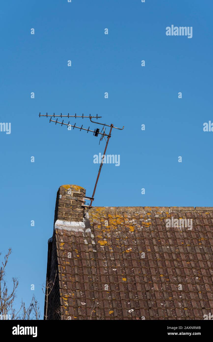 Eine Haus-TV-Antenne, beschädigt durch Storm Ciara, hängt schräg an einem Stummelschornstein. Extern montierte tv-Antenne auf dem Dach des Hauses Stockfoto