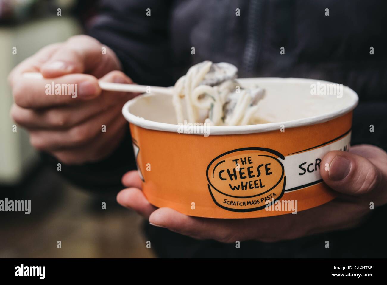 London, Großbritannien - 26. November 2019: Nahaufnahme eines Mannes, der Pasta vom Käseradstand im Camden Market, London, einer der meistfrequentierten Desti im Einzelhandel, isst Stockfoto